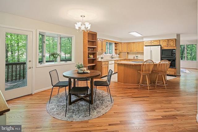 dining area with baseboards, a chandelier, and light wood-type flooring