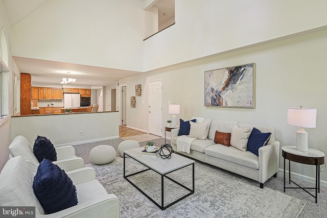 living room with an inviting chandelier, baseboards, and high vaulted ceiling