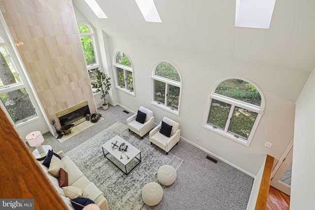 living room with a skylight, high vaulted ceiling, plenty of natural light, and visible vents
