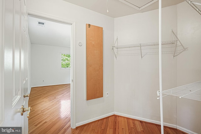 walk in closet featuring visible vents, wood finished floors, and attic access