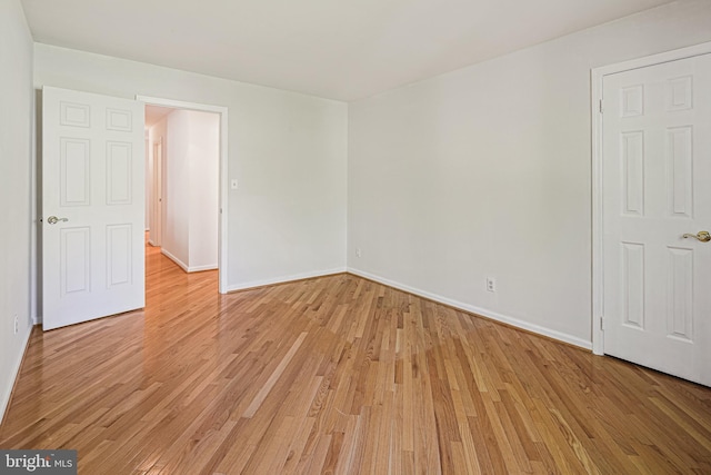 empty room featuring baseboards and light wood-type flooring