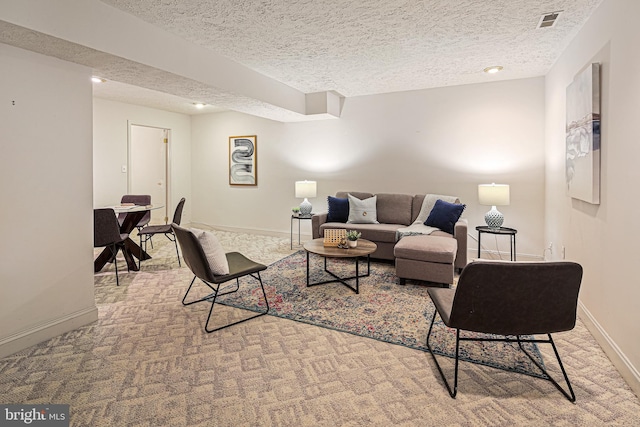 carpeted living room with baseboards, a textured ceiling, and visible vents