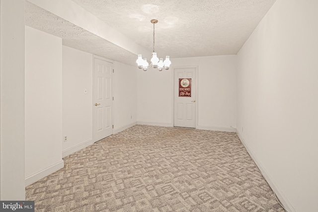 carpeted spare room with baseboards, a textured ceiling, and a notable chandelier