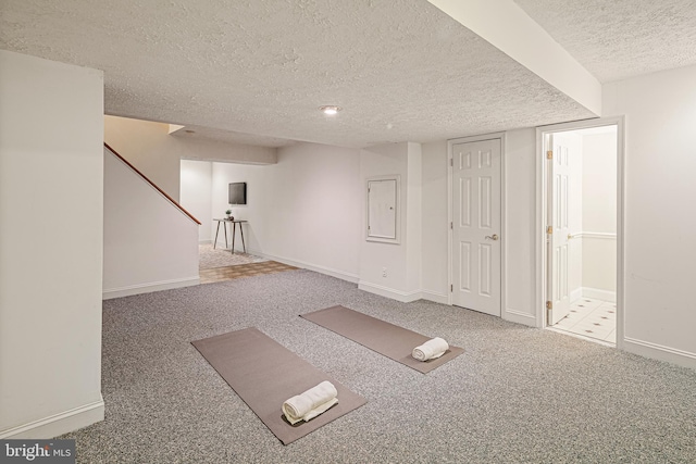 finished below grade area featuring baseboards, carpet, and a textured ceiling