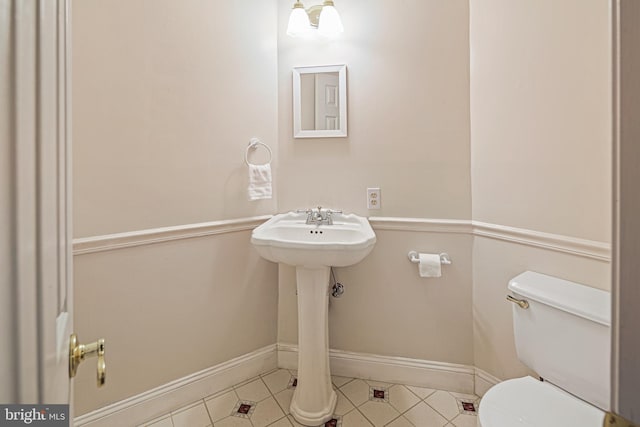 bathroom with a sink, tile patterned floors, baseboards, and toilet