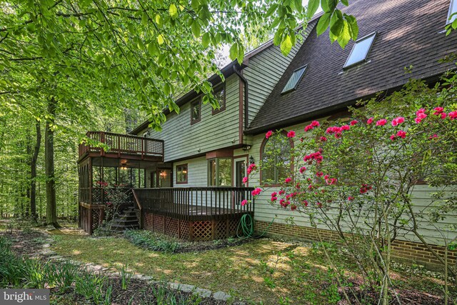 back of property with roof with shingles and a deck
