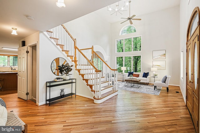 entryway with baseboards, a high ceiling, light wood finished floors, and stairs