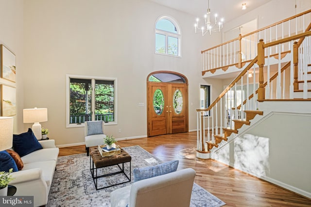entryway featuring a high ceiling, a notable chandelier, wood finished floors, and stairway