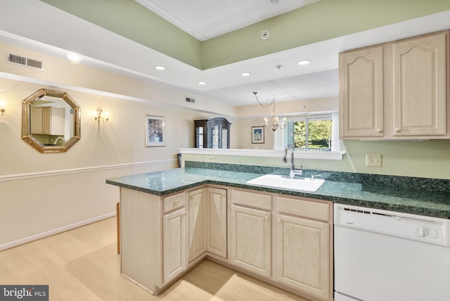 kitchen with light brown cabinetry, white dishwasher, visible vents, and a sink
