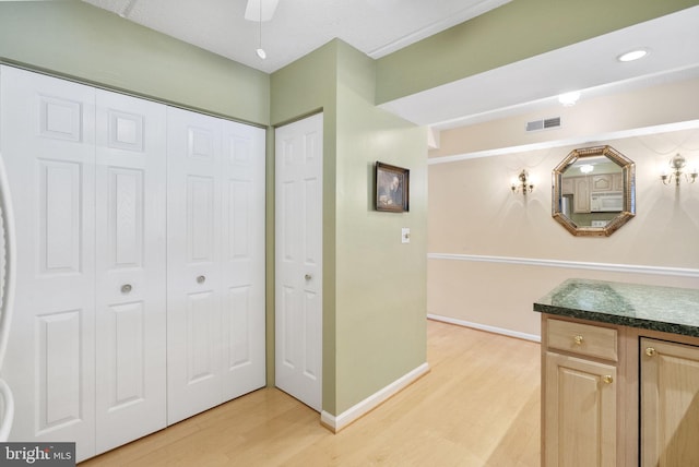 interior space with visible vents, dark countertops, baseboards, light wood-style floors, and white microwave