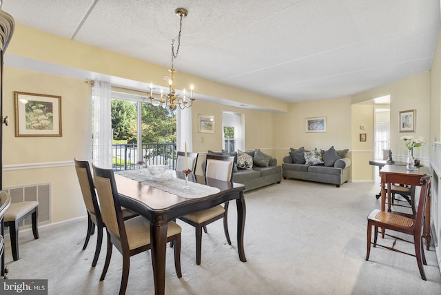 dining room with visible vents, baseboards, light colored carpet, a textured ceiling, and a notable chandelier