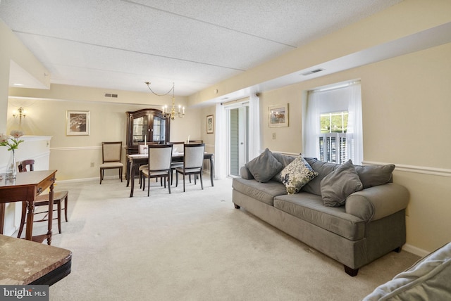 living room with baseboards, a chandelier, light carpet, and visible vents