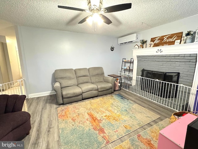 918 Hillside Ave, Upper Chichester, PA 19061 - living room featuring ceiling fan, a brick fireplace, a textured ceiling, a wall unit AC, and wood finished floors