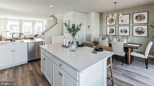 kitchen with a sink, a center island, open floor plan, stainless steel dishwasher, and wood finished floors