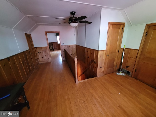 additional living space featuring wainscoting, wooden walls, wood finished floors, lofted ceiling, and ceiling fan