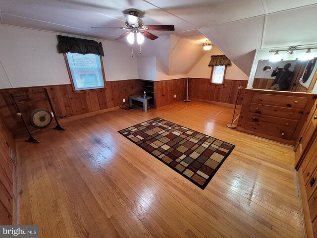 additional living space featuring wainscoting, hardwood / wood-style flooring, a ceiling fan, and wood walls