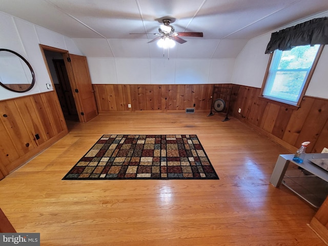 additional living space featuring wood walls, wood finished floors, ceiling fan, a wainscoted wall, and lofted ceiling