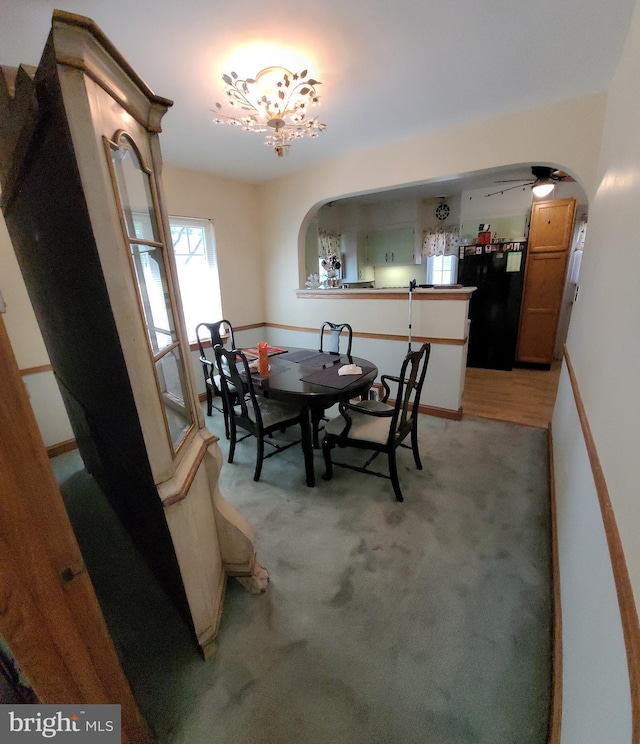 dining room featuring arched walkways and light colored carpet