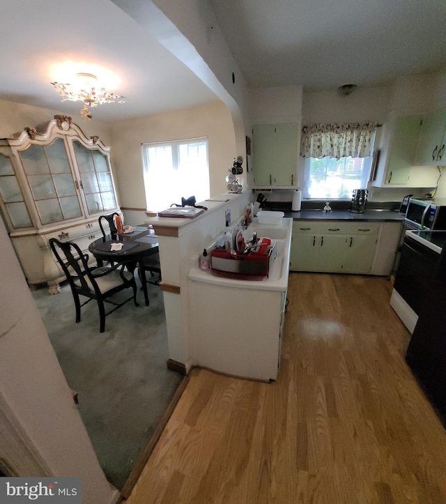 kitchen with range, light wood finished floors, healthy amount of natural light, and arched walkways