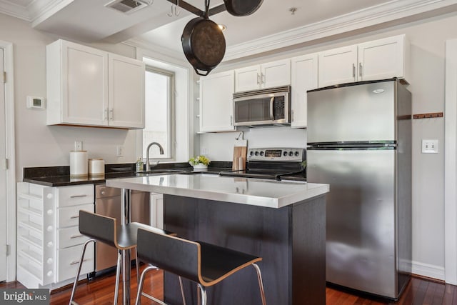 kitchen with visible vents, crown molding, white cabinetry, a sink, and stainless steel appliances