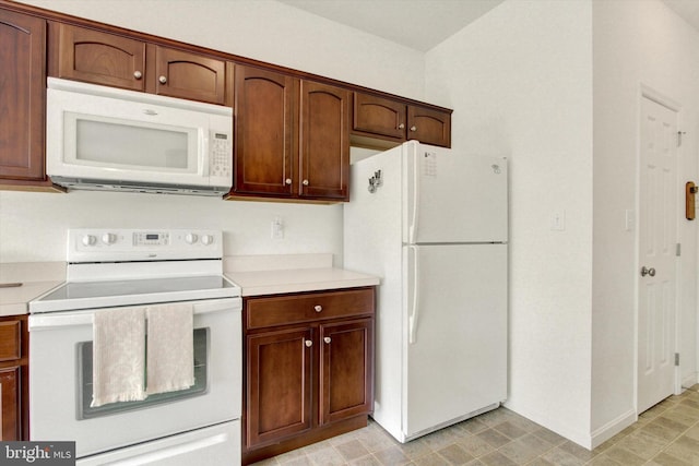 kitchen featuring light countertops, baseboards, and white appliances