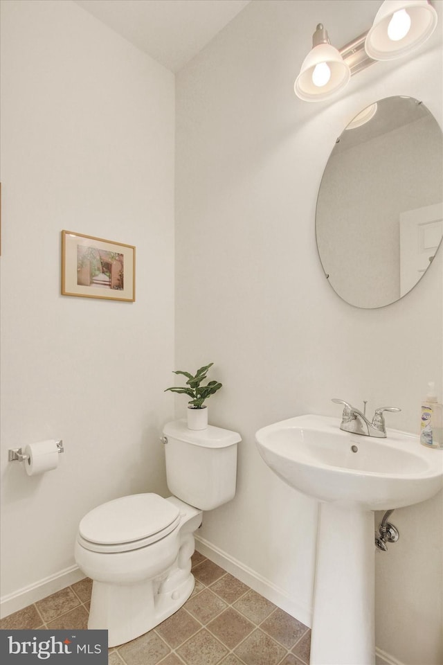 bathroom featuring baseboards, tile patterned floors, and toilet