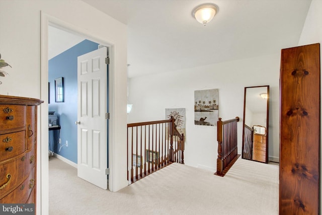 hall with baseboards, an upstairs landing, and carpet