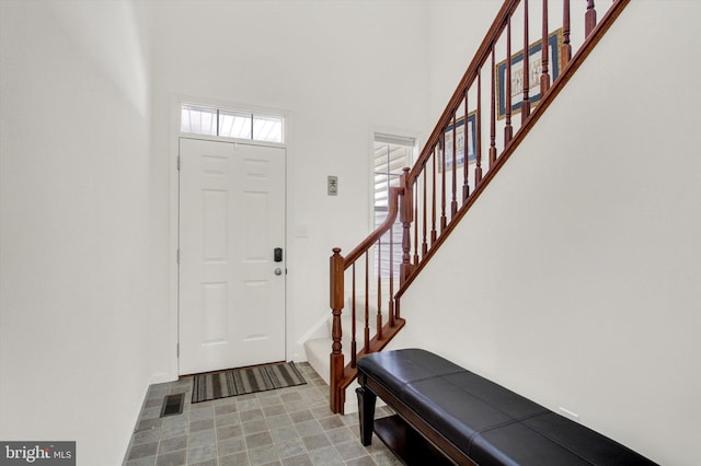 entryway featuring stairway, a high ceiling, and visible vents