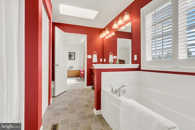 full bath with a bath, visible vents, a skylight, vanity, and baseboards