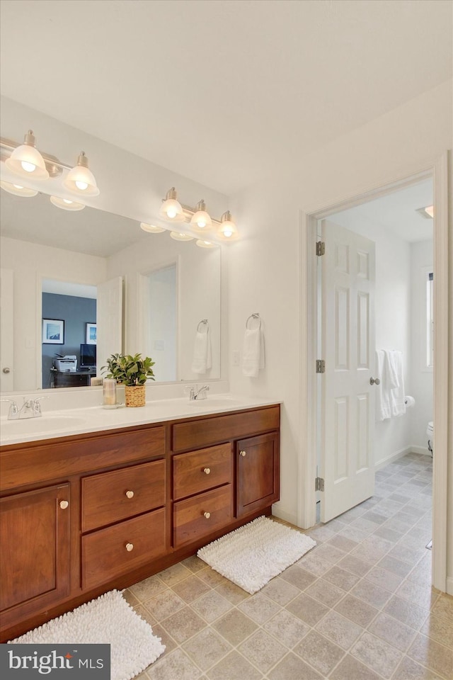 bathroom featuring a sink, toilet, and double vanity