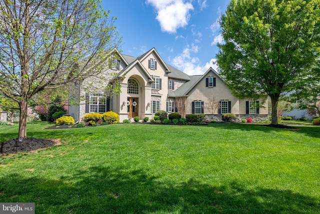 view of front of house featuring a front lawn, stone siding, and stucco siding