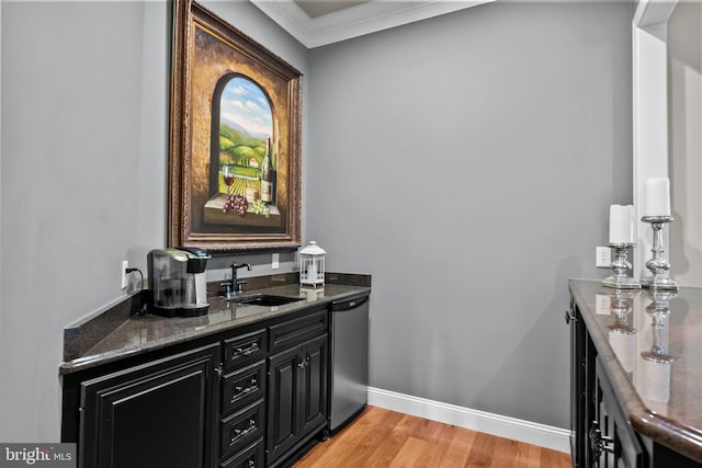 bar with light wood-type flooring, dishwasher, a sink, baseboards, and ornamental molding