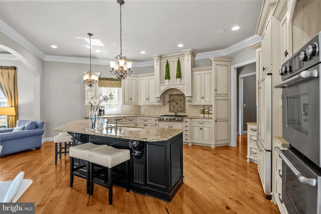 kitchen featuring decorative backsplash, light stone countertops, a chandelier, a breakfast bar, and stainless steel appliances