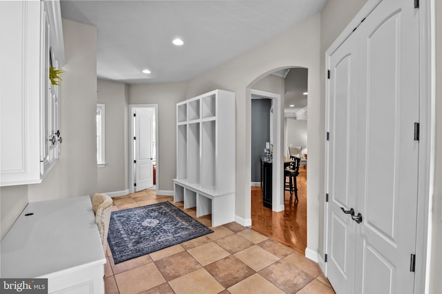 mudroom with arched walkways, baseboards, recessed lighting, and light tile patterned floors