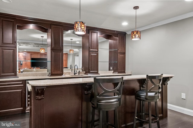 bar with decorative light fixtures, crown molding, a sink, baseboards, and dark wood-style floors