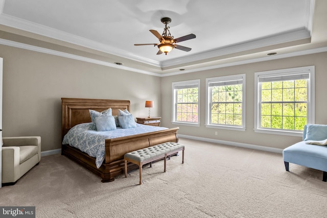 bedroom featuring carpet floors, ornamental molding, a tray ceiling, and multiple windows