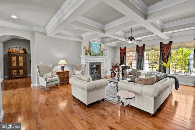 living area with arched walkways, beamed ceiling, light wood-type flooring, and a premium fireplace