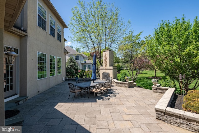 view of patio featuring an outdoor stone fireplace and outdoor dining area