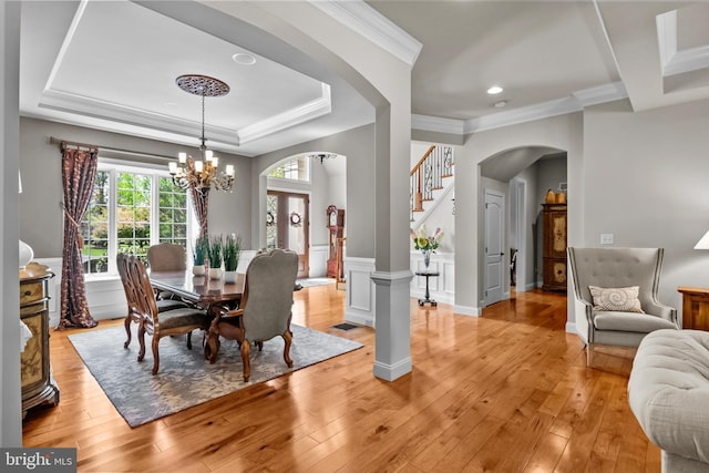 dining area featuring arched walkways, a notable chandelier, ornamental molding, and light wood finished floors