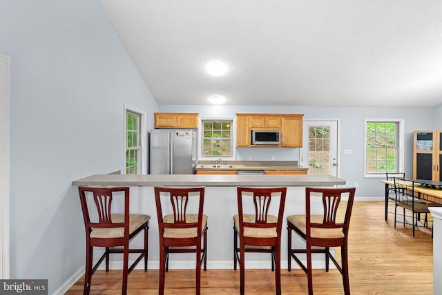806 Windy Way, Front Royal, VA 22630 - kitchen with appliances with stainless steel finishes, light wood-style flooring, light countertops, a breakfast bar area, and a textured ceiling