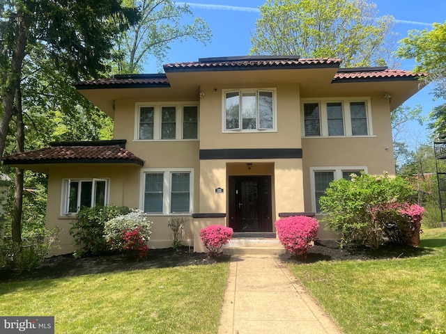view of front of property featuring stucco siding, a front yard, and a tiled roof