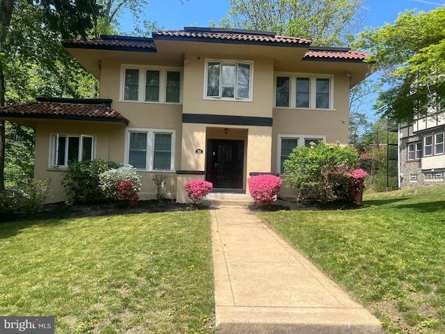 view of front of house featuring stucco siding, a front lawn, and a tile roof