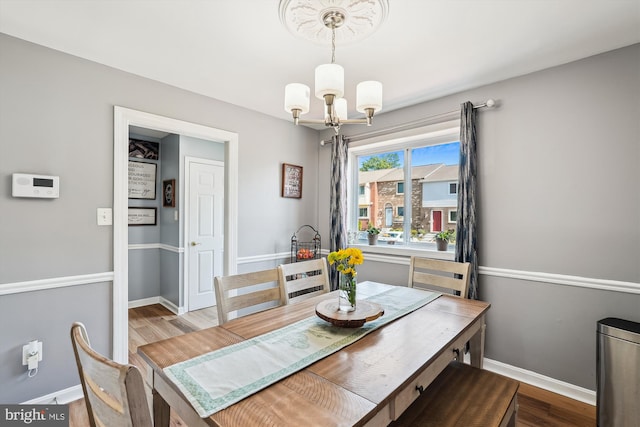 dining room featuring an inviting chandelier, baseboards, and wood finished floors