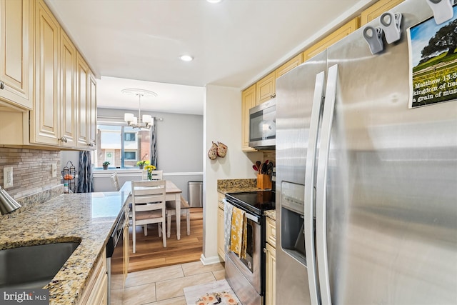 kitchen with appliances with stainless steel finishes, a sink, a chandelier, light tile patterned floors, and cream cabinetry