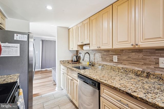 kitchen with backsplash, cream cabinetry, appliances with stainless steel finishes, and a sink