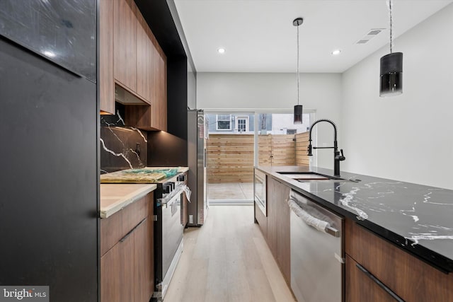 2230 Kimball St, Philadelphia, PA 19146 - kitchen featuring appliances with stainless steel finishes, a sink, light wood-style floors, decorative backsplash, and modern cabinets