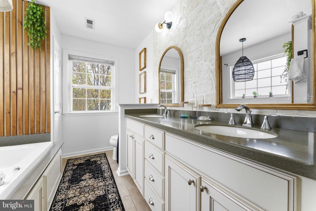 bathroom featuring visible vents, a sink, double vanity, and toilet