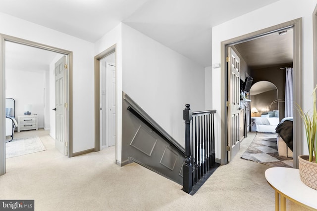 hallway with carpet floors, baseboards, and an upstairs landing
