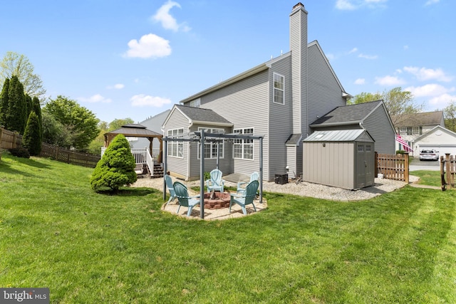 rear view of property featuring fence, a gazebo, a shed, an outdoor structure, and a fire pit