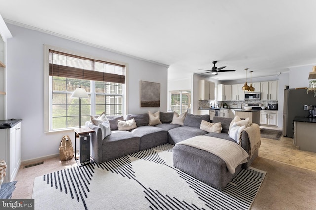 living area featuring ceiling fan, a wealth of natural light, and light carpet